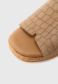 Ταμπά σανδάλι τύπου slip-on με ανάγλυφο επάνω μέρος από σουέντ, λεία δερμάτινη σόλα και φελλό στη βάση. Διαθέτει ανοιχτή μύτη και μινιμαλιστικό σχέδιο.