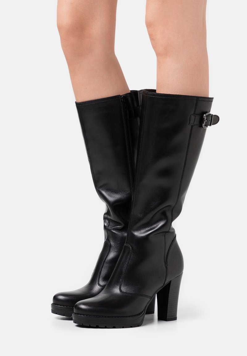 Black knee-high boots made of glossy leather, featuring a side zipper, a buckle accent, and a chunky high heel with textured sole.