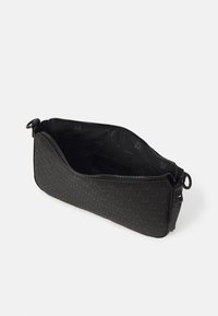 Pochette noire zippée avec motif embossé, ouverte montrant une doublure intérieure en tissu lisse avec des impressions subtiles de logos.