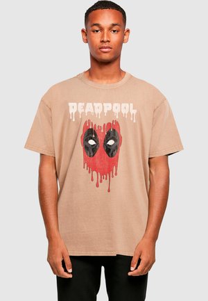 Brūna kokvilnas T-krekls ar sarkano un melno Deadpool logo, kas izskatās, it kā tas pilētu. īsas piedurknes un apkakles dizains.