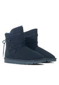 Stivaletti ankle blu scuro in suede con un morbido interno peluche. Presentano una punta arrotondata e lacci decorativi sulla parte anteriore e sui lati.