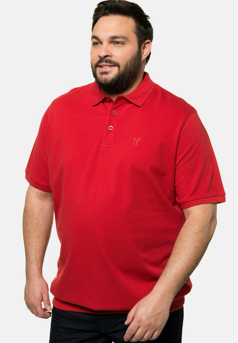 Polo rosso con colletto, due bottoni sul davanti e un marchio discreto. Realizzato in tessuto a trama, con maniche corte.