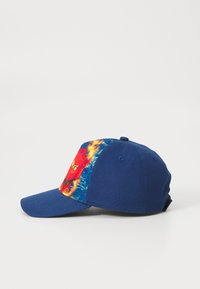 Kék baseball sapka, strukturált elülső résszel, színes grafikai nyomattal az oldalon és kemény napellenzővel. Pamutszövetből készült.