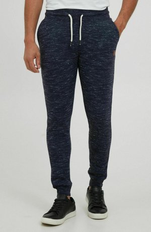Navy flecked joggers in soft fabric, featuring a drawstring waist, tapered legs, and side pockets, paired with black athletic shoes.