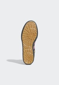 Svart och gummirubber sneaker sula med en strukturerad design och djupa mönster. Inkluderar rosa och guldaccenter längs sidorna.