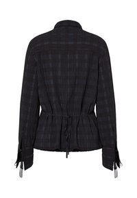Blouse noire à manches longues avec plis verticaux, motif à carreaux subtil, ceinture cintrée à la taille et liens ajustables aux poignets, vue de dos.