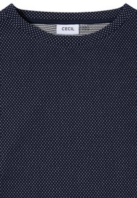 Granatowy materiał tekstylny z fakturą w kropki, z okrągłym dekoltem i metką z napisem "CECIL" wewnątrz kołnierza.