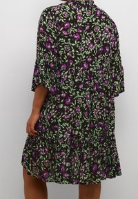 Schwarzes Blumenkleid mit lila und grünen Blumen, das ein gestuftes Design und kurze, zarte Ärmel hat. Hergestellt aus leichtem Stoff.