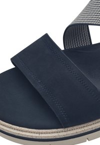 Navy blue sandal featuring a wide strap design, textured elastic band, and a speckled beige sole. Smooth surface with stitching accents.