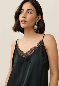 Camisón de satén negro con escote en V que presenta un intrincado borde de encaje negro y tirantes tipo espagueti, exhibido sobre un fondo neutro.