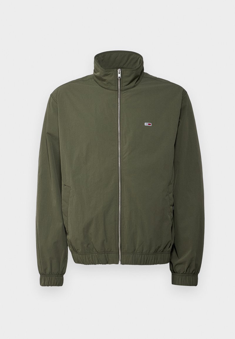 Veste olive, col élevé, fermeture éclair sur le devant, poignets élastiques, deux poches latérales, écusson logo sur la poitrine, tissu léger, design simple.