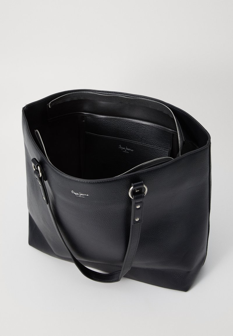 Sac fourre-tout en cuir noir avec une texture lisse, fermeture zippée sur le dessus, quincaillerie en acier inoxydable et poches intérieures pour l'organisation. Logo embossé à l'intérieur.
