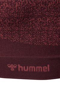 Tissu tricoté dans des tons bordeaux avec un motif en dégradé et le nom de la marque « hummel » ainsi que le logo d'abeille tissés près du bord.