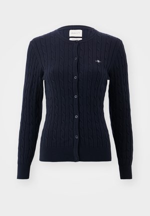 Marineblauwe gebreide cardigan met kabelpatroon, ronde halslijn en sluiting met zes knopen. Bevat een klein geborduurd logo op de borst.