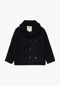 Tmavě modrý dvouřadý kabát z vlny, s velkými předními kapsami a stříbrnými knoflíky. Kabát má klopový límec a měkkou texturu.