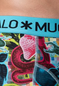 Színes boxer alsónadrág kék rugalmas derékpánttal, fekete szöveggel. Az anyag élénk gyümölcsök, kígyók és textúrák mintázatát mutatja.