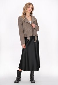 Taupe nubuck motorcykeljakke med lynlåslommer, bælte i taljen og sølvhardware, stylet med en sort satin maxi-nederdel og sorte støvler.
