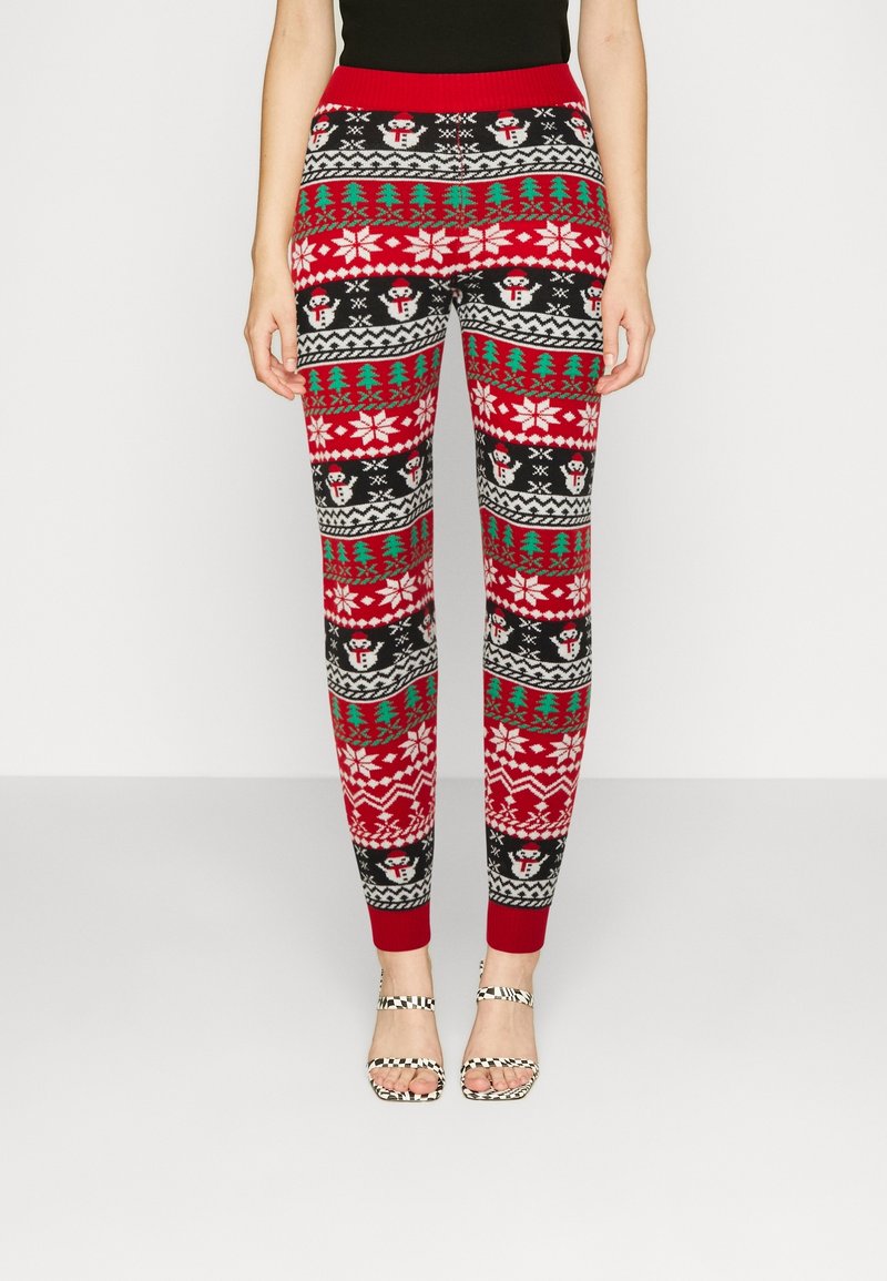 Leggings à motif rouge, noir et vert présentant des bonhommes de neige, des flocons de neige et des arbres, avec une taille rouge et des poignets côtelés.