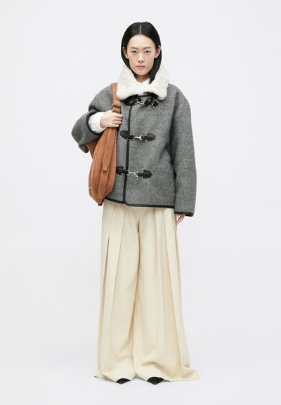 Pilkas vilnonis paltas su baltu dirbtinio kailio apykakle, su juodais užsegimais. Suderintas su kreminiu plačiomis kelnėmis ir rudos zomšos krepšiu.