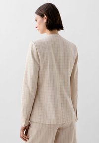 Beige károvaný blazer se strukturovaným designem, zdobený jemnou mřížkovou vzorkem v světlehnědé a krémové barvě. Vyrobeno z hladkého, upraveného materiálu.