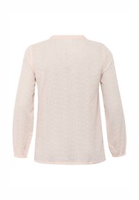 Long-sleeve blouse in pale pink, featuring a textured fabric with small cut-out patterns and a straight hem. Round neckline with subtle trim.
