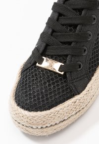 Sneaker nera in rete con punta testurizzata, suola in juta intrecciata e dettagli metallici nell'area dei lacci.
