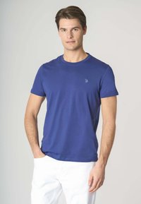 T-shirt in cotone blu con scollatura rotonda, maniche corte e un piccolo dettaglio del logo sul petto. Tessuto strutturato, design aderente.