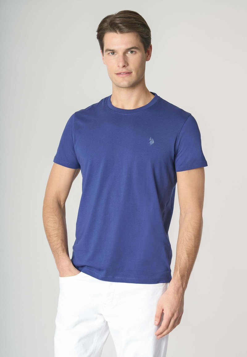 T-shirt in cotone blu con scollatura rotonda, maniche corte e un piccolo dettaglio del logo sul petto. Tessuto strutturato, design aderente.