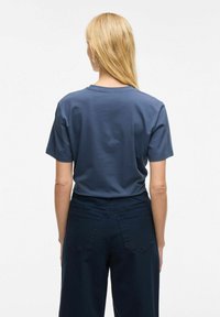 Camiseta de algodón azul marino de manga corta y cuello redondo, combinada con pantalones de pierna ancha en azul oscuro que cuentan con bolsillos traseros.