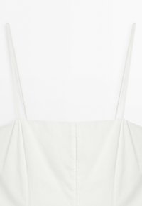 White sleeveless top with thin spaghetti straps and a straight neckline, displayed on a plain white background.
