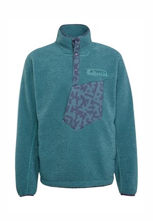 Teal fleecetakki, jossa on korkea kaulus, puolivälin napitus ja kuvioitu rintatasku tummemman teal- ja purppura-sävyissä.