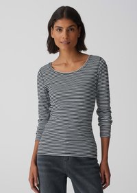 Schwarz-weiße gestreifte Langarmbluse mit rundem Ausschnitt, aus weichem Stoff, enganliegendem Schnitt und kombiniert mit dunklen Denim-Jeans.