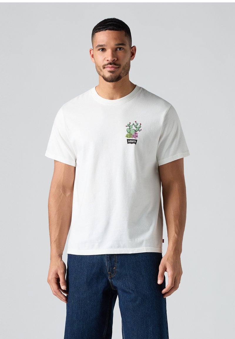 Camiseta de algodón blanca con un gráfico de cactus en verde y púrpura, con un logo negro de Levi's en el pecho. Mangas cortas y cuello redondo.