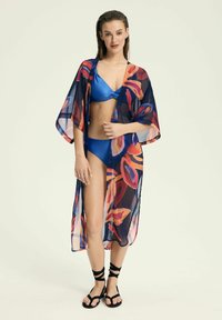 Przezroczysty kimono w kolorowe wzory liści na ciemnym granatowym tle. Połączone z niebieskim bikini i czarnymi sandałami na paski.