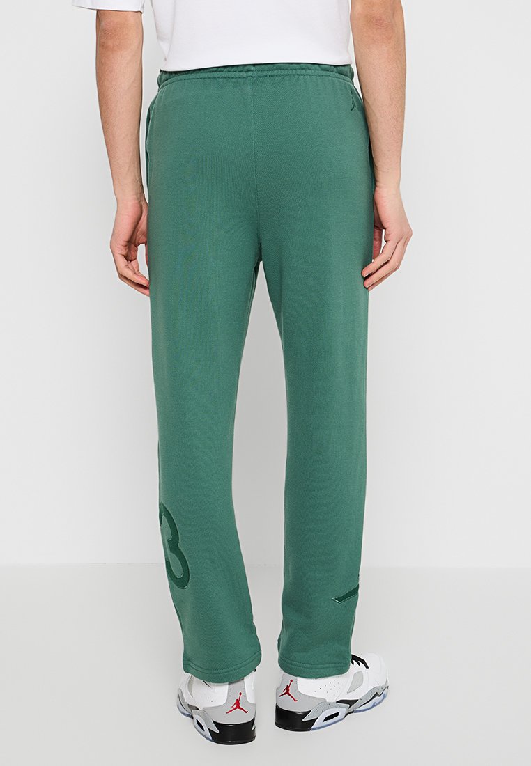 Pantalons de jogging verts avec une finition texturée, présentant un grand numéro imprimé sur la jambe gauche et une taille à cordon de serrage.