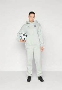 Set Nike grigio chiaro con felpa con cappuccio e pantaloni della tuta, con logo sul petto, abbinato a un pallone da calcio e scarpe nere.