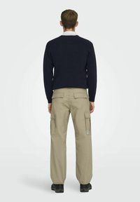 Laivastonsininen neule ja khakinväriset cargo-housut, joissa on useita taskuja. Housuissa on rento istuvuus ja kestävä kangas, joita täydentää logotägi.