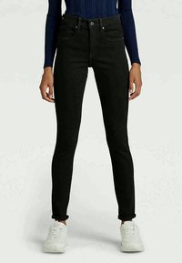 Jeans negros ajustados de denim, de cintura alta con cinco bolsillos, con cremallera y detalles de costura sutiles. Corte casual.