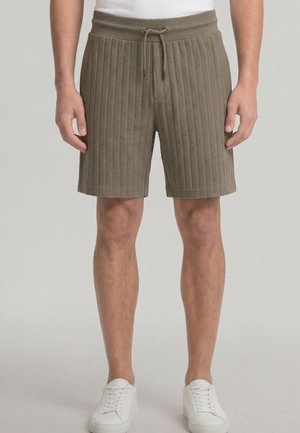 Herren gerippte olivgrüne Shorts mit Kordelzug, kombiniert mit weißen Sneakers und einem weißen Hemd, das am Bund sichtbar ist.
