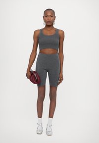 Sivé rebrované crop top a zodpovedajúce vysoké šortky, skombinované s bordovou kabelkou a striebornými balerínkami, na bielom pozadí.