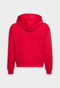 Sweatshirt à capuche rouge, fabriqué à partir d'un matériau doux. Présente un design court, des poignets côtelés et une texture lisse sans motifs visibles.