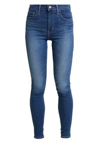 Jeans de mezclilla azul de corte slim y cintura alta con botón y cremallera frontal, cinco bolsillos y un sutil desgaste en los muslos y las rodillas.