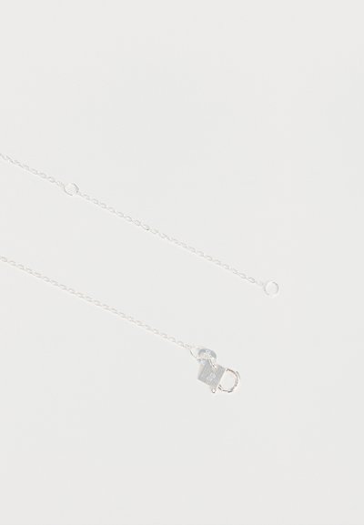 Chaîne de collier en argent délicate avec un fermoir en forme de cœur et un poinçon "925" sur le fermoir sur fond blanc uni.