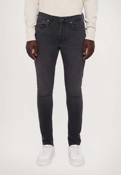 Mørkegrå skinny jeans i denimstof med forlommer og knaplukning. Kombineret med hvide sneakers, hvilket giver et afslappet look.