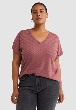 Top de manga corta y escote en V en rosa empolvado con un patrón de espiga texturizado. Tejido suave con mangas enrolladas, combinado con pantalones grises oscuros.
