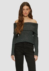 Dunkelgrauer, gerippter Pullover mit schulterfreiem Schnitt, umgeschlagenem Kragen und langen Ärmeln, kombiniert mit eng anliegenden schwarzen Jeans.