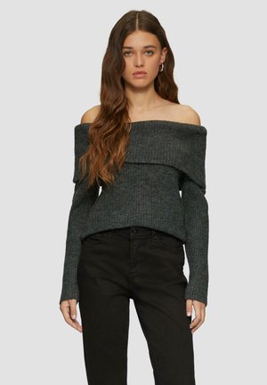 Off-the-shoulder donkergrijze geribbelde trui met een opgevouwen halslijn en lange mouwen, gecombineerd met zwarte aansluitende jeans.