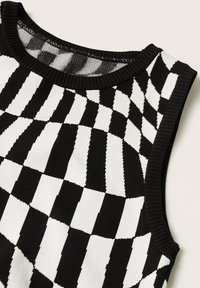 Haut en maille sans manches noir et blanc avec un motif à carreaux déformé et un col et des emmanchures côtelés.
