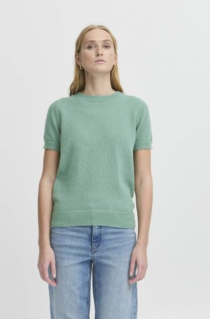 Pull à manches courtes, col rond, en maille douce verte, présentant une coupe décontractée et des bords ribbelés au niveau du col et de l'ourlet.