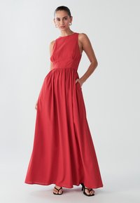 Vestito maxi rosso senza maniche con corpetto aderente, gonna arricciata e tasche. Realizzato in tessuto leggero, caratterizzato da una texture liscia.